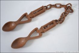 A pair of welsh spoons joined by a chain with a heart shaped central link.
