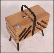 A vintage 1950's metamorphic sewing box raised on tapered legs with multi-sectional hinged top.