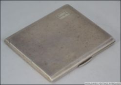 A silver hallmarked cigarette case with monogram cartouche being engine turned.