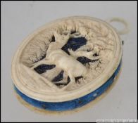 A 19thC French bone pin cushion, finely carved with a stag in a glade and a geometric leaf pattern,