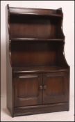 An Ercol dark Jacobean revival beech and elm waterfall bookcase cabinet with drawer to the base