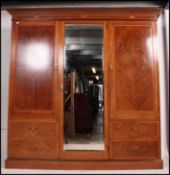 An Edwardian mahogany inlaid Waring & Gillows triple wardrobe compactum being raised on plinth base
