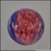 A 19th century two colour hand blown glass marble in red and white with clear glass measuring