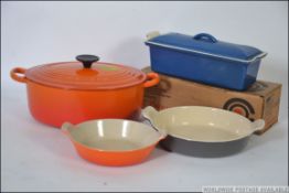 A Le Crueset casserole dish of large form together with a pate terrine and other Le Creuset items.