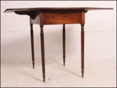 A 19th century mahogany drop leaf pembroke table being raised on reeded turned legs with drop