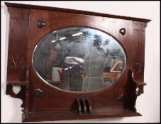 A Victorian oak Arts & Crafts overmantel mirror with shaped bevelled plate mirror having shelf base