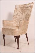 An early 20th century iron framed wingback armchair raised on cabriole legs with thin upright