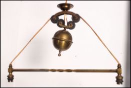 A vintage early 20th century brass twin sconce rise and fall light fixture having central twist bar