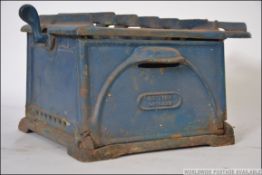A vintage 20th century cast metal portable British Grilling stove having a single burner next to