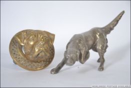 A silver white metal figurine of a hunting dog along with a brass door knocker in the form of a dog