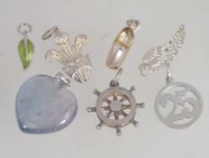 A collection of silver necklace pendants to include shoe, agate, ships wheel, fleur de lys etc.