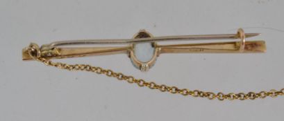 A tested 15ct gold bar brooch with oval cut aqua marine stone with C clasp and safety chain.