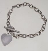A silver heavy chain linked bracelet with heart pendant uniting by bale and bar clasp.