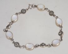 A silver 925 bracelet chain having illusion set stone spacers and mother of pearl roundels with a C