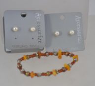 An amber bracelet of baroque form together with a baroque pearl single string necklace and a pair