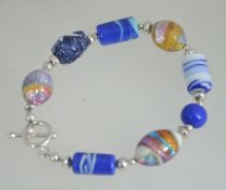 A silver and Murano style art glass ladies bracelet having coloured glass and silver spacers with