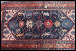 A Persian handwoven floor rug being woven in the traditional style featuring reds / blues / greens