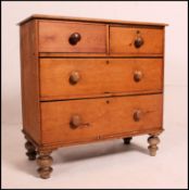 A Victorian pine 2 over 2 cottage chest of drawers being raised on bun feet with knob handles to