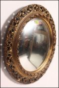 A 1950's mahogany convex wall mirror having gilt rococo frame with fish eye mirror to centre.