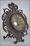 A 19th century brass easel clock of rococo form having a mask head to the base,