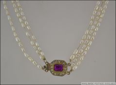 Baroque Pearl triple string necklace with pave set clasp with large central stone .