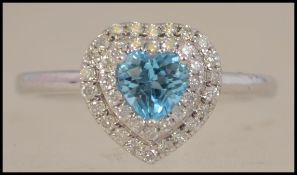 A hallmarked 9ct white gold heart shaped diamond cluster ring with large central aquamarine stone.
