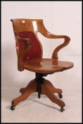 A 1920's oak Industrial swivel office chair raised on a quadruped base having saddle seat and