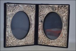 A silver hallmarked folding picture frame with a blue velvet backing and a floral repose design