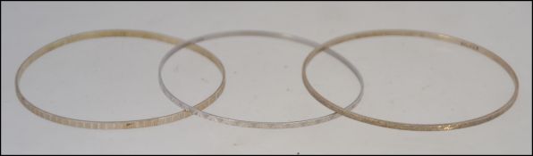A group of three silver bangles, two stamped 925 and the other silver,