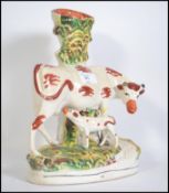 A 19th century Staffordshire spill vase with a cow and a young calf milking on a naturalistic