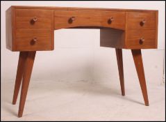 A 1970's teak wood Beresford & Hicks writing table being raised on squared legs with a series of