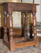 A 17th / 18th century country oak peg jointed stool raised on gun barrel turned legs united by