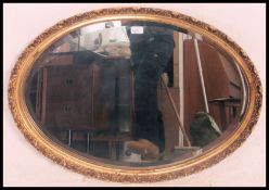 An antique style gilt oval wall mirror of rococo form having bevelled mirror glass centre.