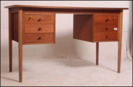 A 1970's teak wood writing table desk raised on turned legs having raised pedestals of drawers