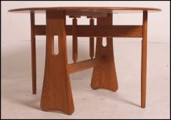 An Ercol elm Windsor light finish gate - leg dining table on beech supports.