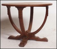 An Arts & Crafts solid oak circular occasional table being raised on bentwood supports having pad