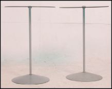 A pair of matching frosted glass side / occasional tables being raised by a singular metal supports
