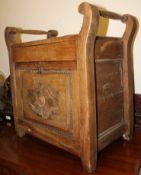 An Edwardian carved oak piano stool with fall front music storage space on stub supports