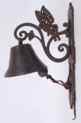 A cast iron exterior hanging garden bell with decorative butterfly bracket.