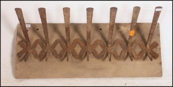 A Hungarian large oversized coat rack. Cast iron oversized hooks set to a rustic panel.