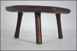 An 18th century rustic childs north country elm peg leg jointed stool of shaped form being raised
