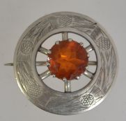 A white metal scottish thistle brooch with central orange stone with etched thistle decoration and