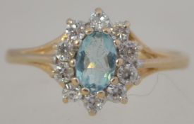 A 9ct gold and aquamarine ladies dress ring, the central stone surrounded by cz stones.