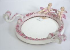 A 19th century believed Meissen continental ceramic wall mirror having twin swivel candle sconses.