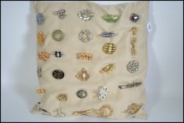 Cushion full of approx 30 costume jewellery brooches to include , white metal , good luck charms ,