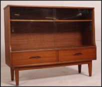 A 1970's retro G-Plan teak window bookcase cabinet raised on tapered legs with drawers under