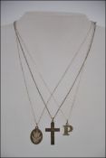 A collection of three silver necklaces and pendants, consisting of a 9t gold cross pendant,