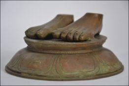 A 20th Century Hindu / Nepalese bronze sculpture of two small feet raised on base with symbols