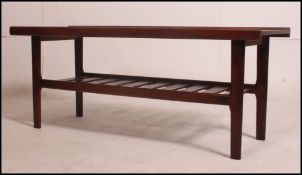 A vintage 1970's Danish teak wood coffee table raised on shaped legs with slatted magazine rack