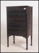 An Edwardian ebonised mahogany music cabinet being raised on tapered legs with a bank of drawers